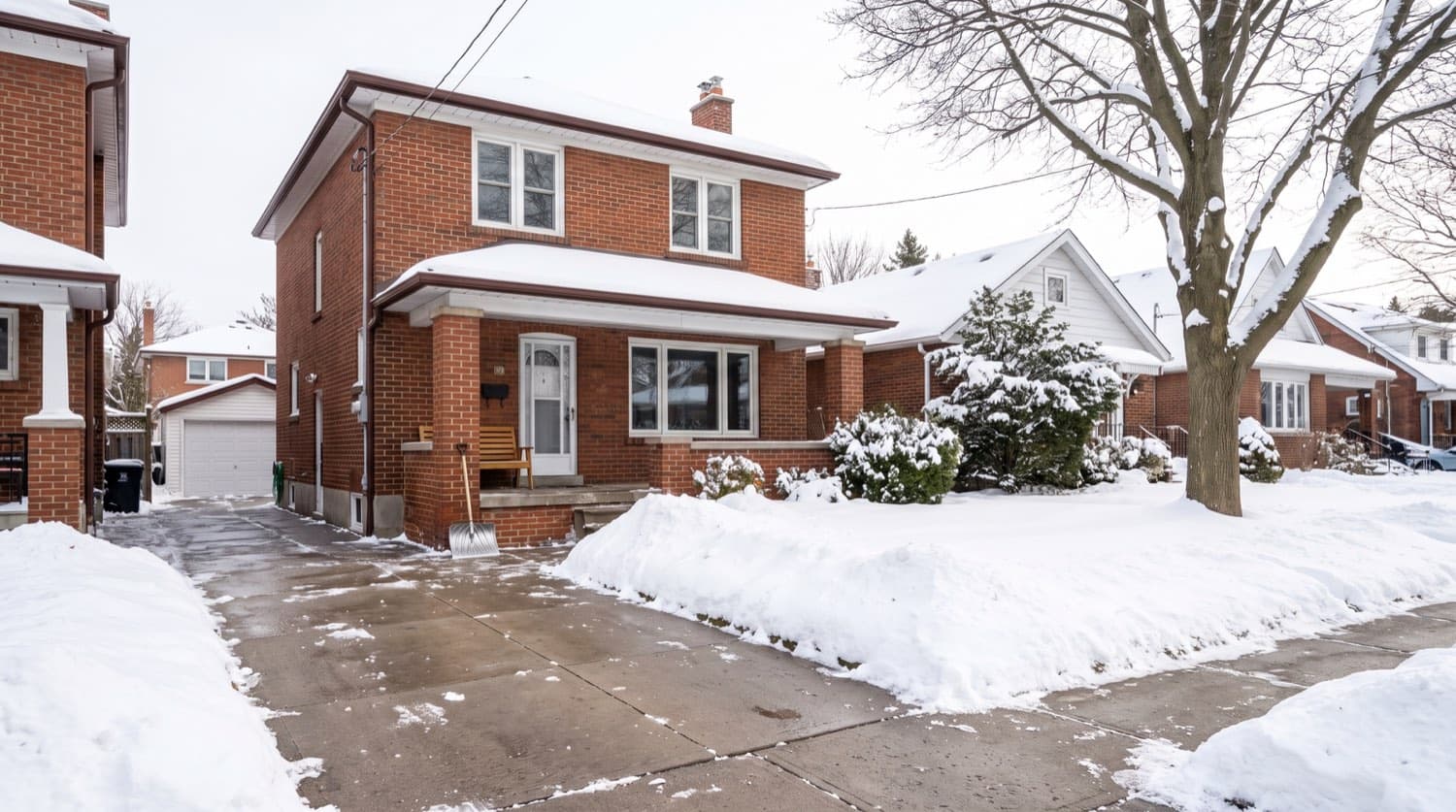 Freshly cleared double driveway beside a snow-covered Toronto brick house on a crisp winter morning