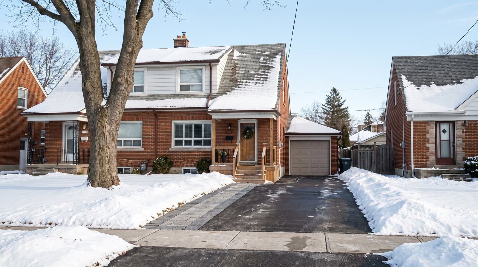Cleared residential driveway beside a snow-covered Toronto brick house on a crisp winter morning